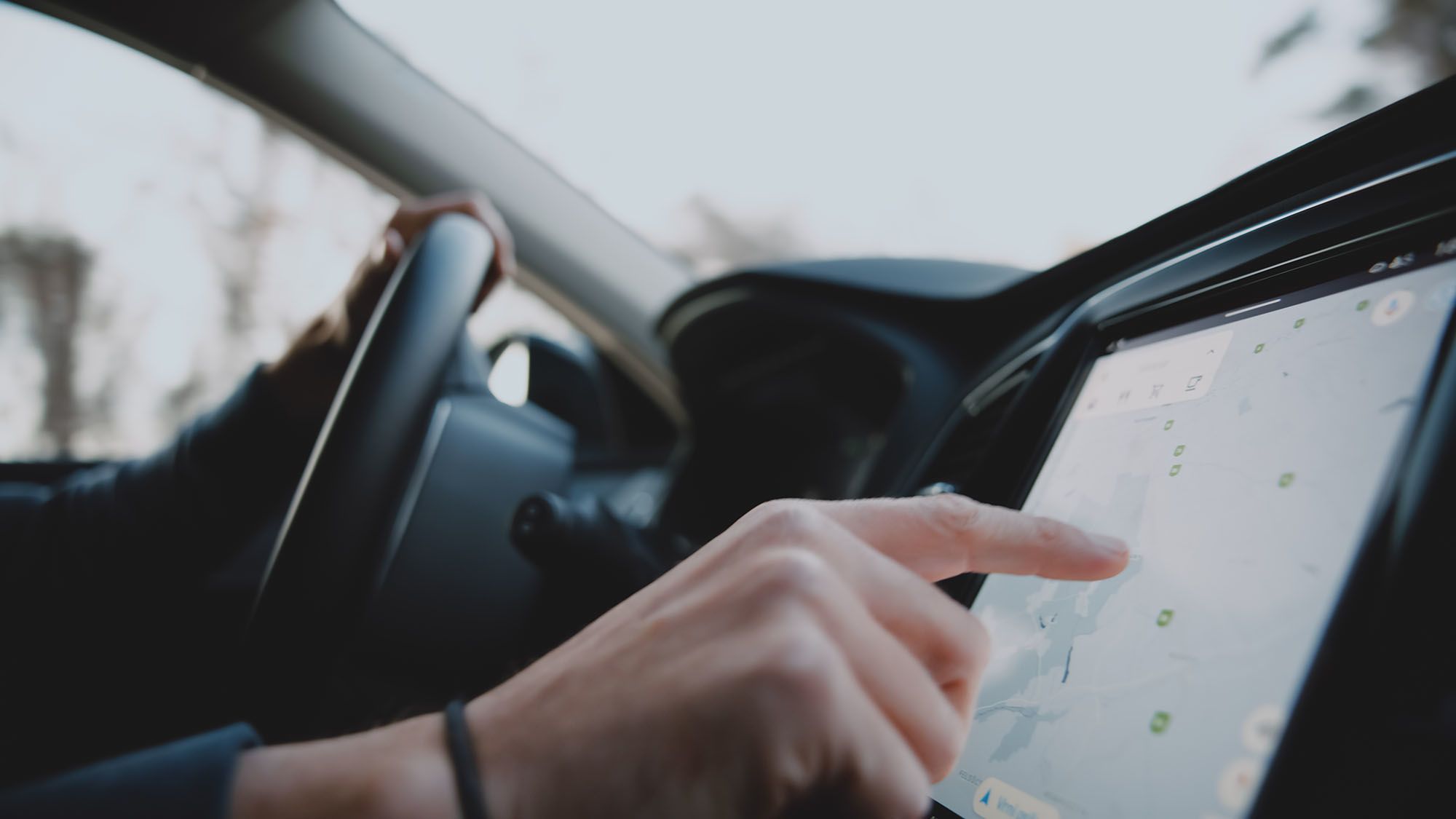 Hand using a touchscreen inside a car