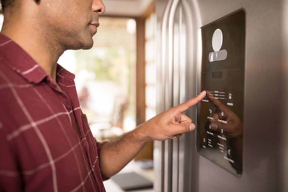Man pressing the digital pad on a smart refrigerator