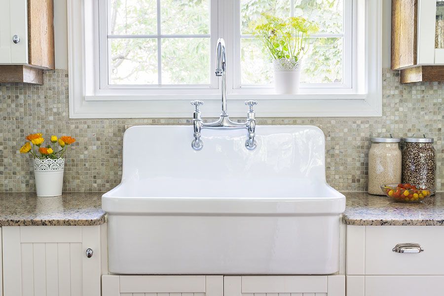 Shiny white farmhouse kitchen sink under window
