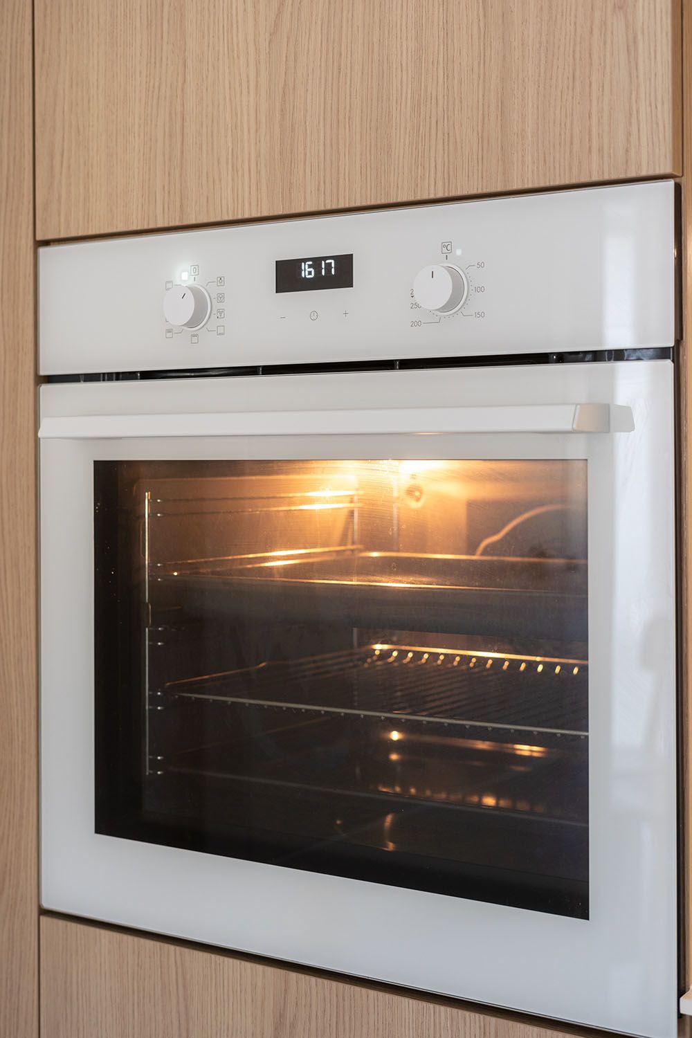 White built in oven against a sleek, modern wooden cabinet