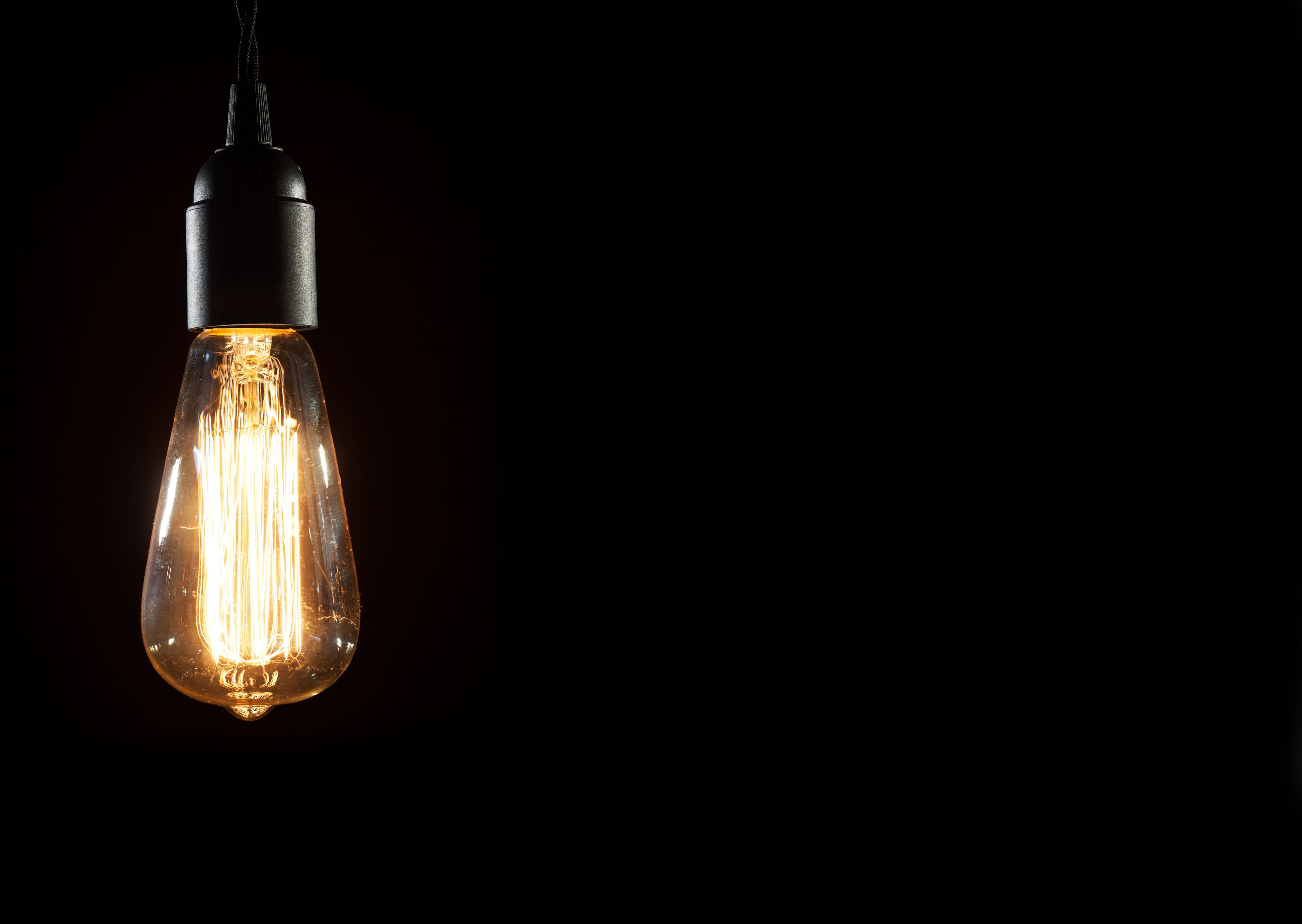 Lit Edison bulb on black background