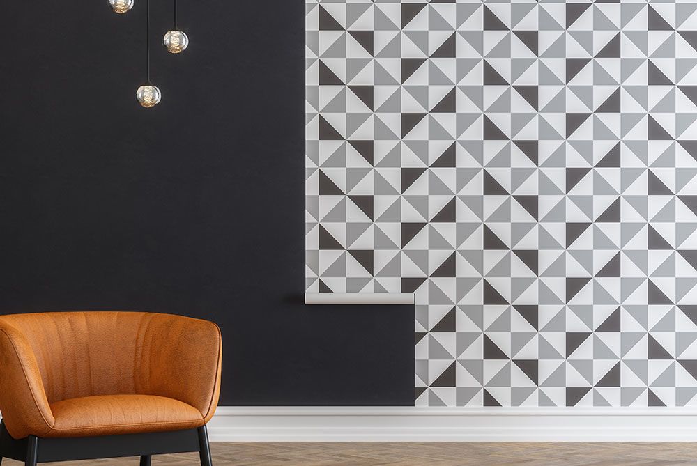 Grey wallpaper halfway completed with an armchair